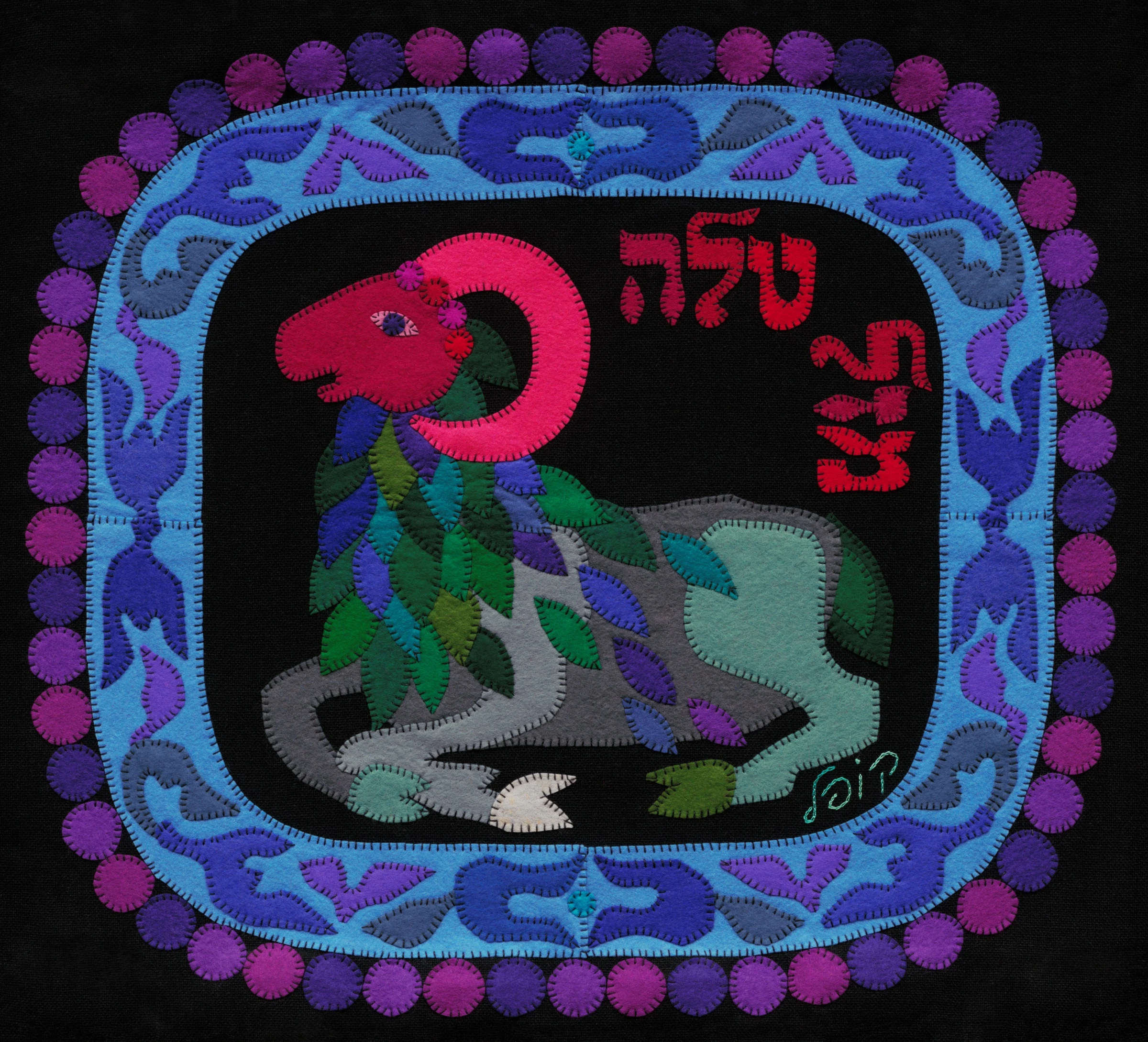 Aries by Kopel Gurwin, a hand-cut felt appliqué depicting a stylized ram with a vivid pink head, a large curved horn, and a body composed of layered green, blue, violet, and gray forms. The figure appears against a black background within an ornate blue and purple border encircled by circular motifs, accompanied by red Hebrew lettering identifying the zodiac sign as Mazal Tale.