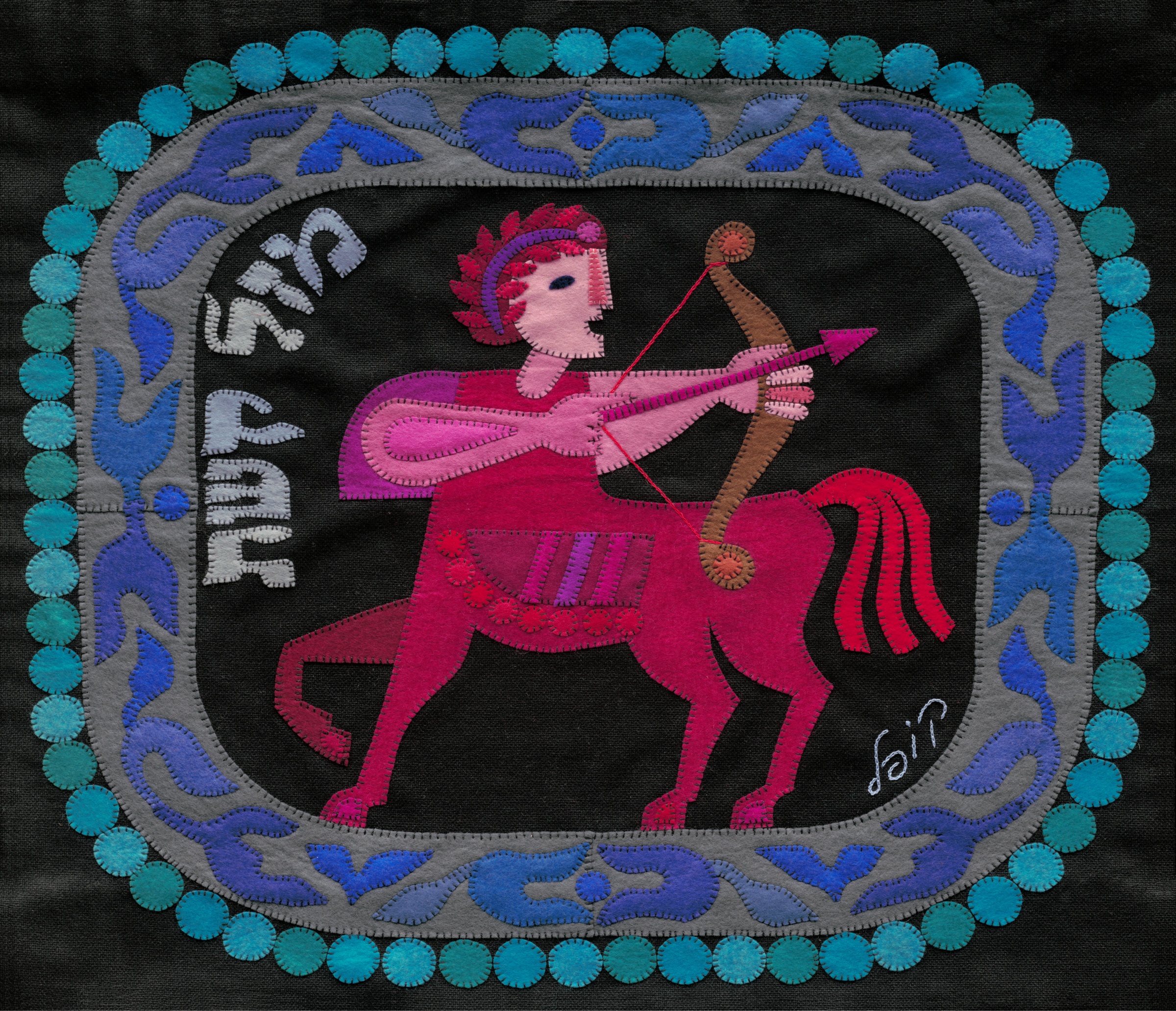 Sagittarius by Kopel Gurwin, a hand-cut felt appliqué depicting a pink and crimson centaur drawing a bow and aiming an arrow to the right. The figure stands against a black background within an ornate blue and gray border encircled by turquoise circular motifs. Hebrew lettering identifies the zodiac sign as Mazal Kashat.