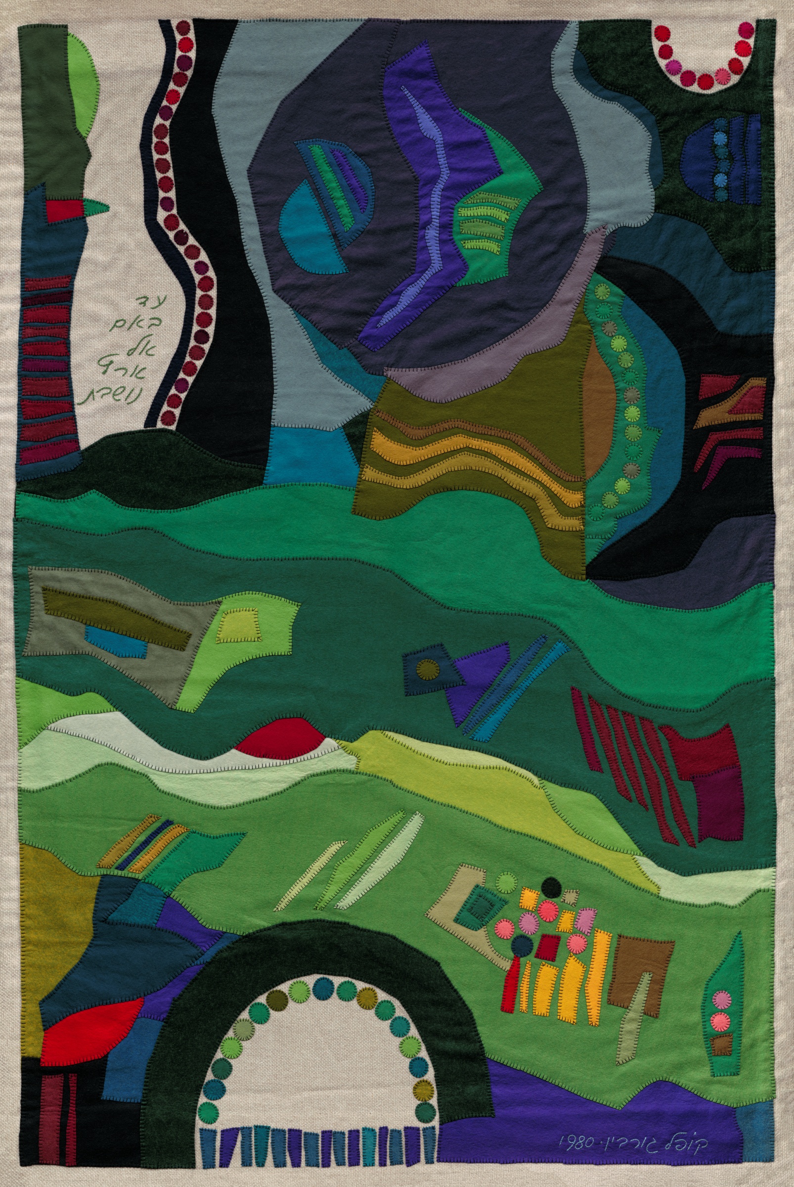 A Land Inhabited by Kopel Gurwin, an abstract hand-cut felt appliqué composed of overlapping organic and geometric forms in green, turquoise, blue, violet, burgundy, and ochre. Broad undulating bands cross the composition, punctuated by circular motifs, patterned rectangles, and a pale arch near the lower edge. A handwritten Hebrew inscription appears at the upper left.