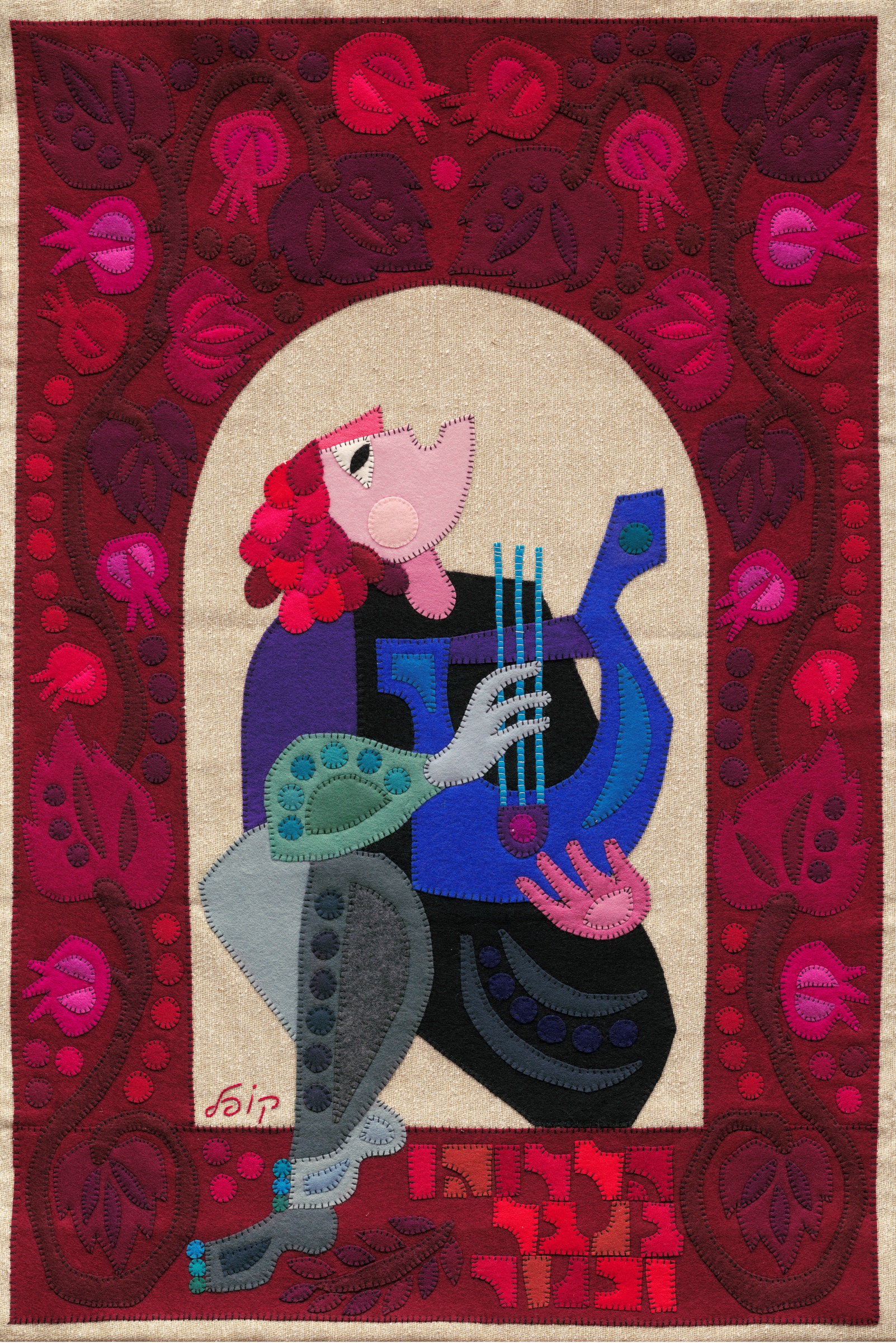 Praise God by Kopel Gurwin, a hand-cut felt appliqué showing King David seated and playing a blue lyre within a pale arched field. The composition is framed by deep red ornamentation filled with stylized pomegranates and foliage, while a Hebrew inscription appears below the figure.