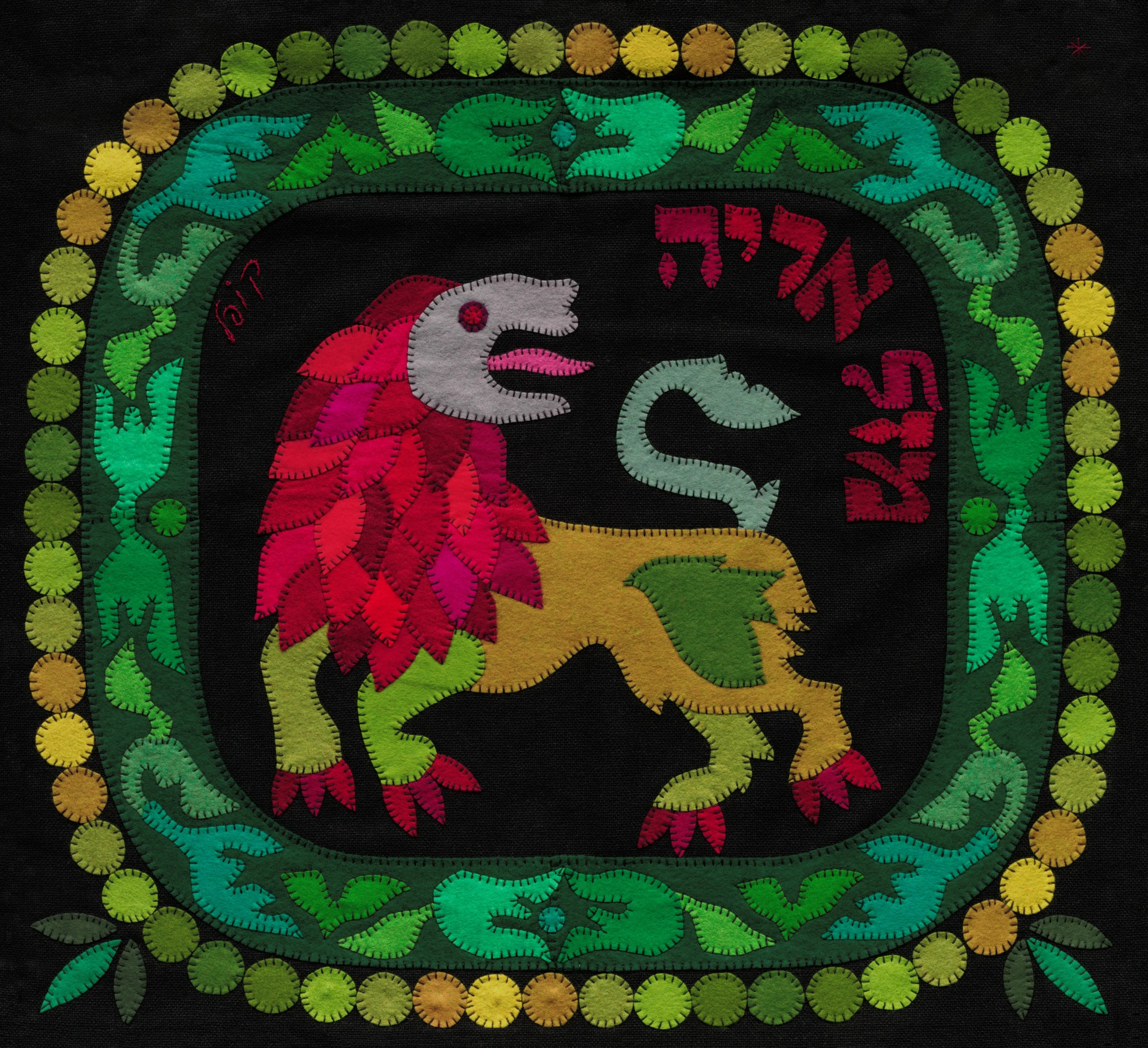 Leo by Kopel Gurwin, a hand-cut felt appliqué depicting a stylized lion with a red and magenta mane, a yellow and green body, and an upturned tail. The lion stands against a black background, surrounded by an ornate green, turquoise, and purple border edged with yellow and green circles. Red Hebrew lettering identifies the sign as Mazal Arye.