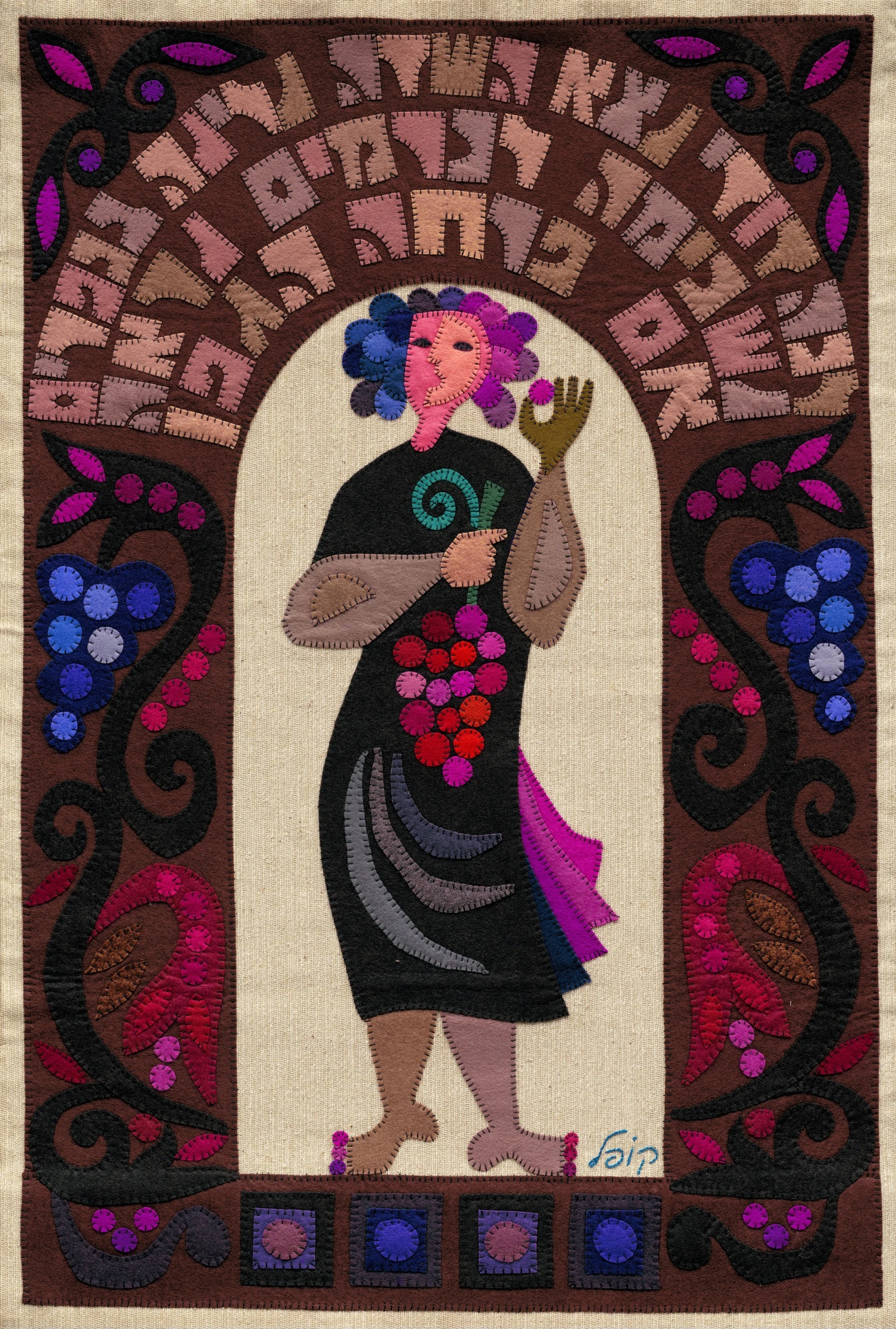 My Beloved by Kopel Gurwin, a colorful hand-cut felt appliqué depicting a young woman holding a cluster of grapes. Her dark silhouette stands against an ivory background, surrounded by ornamental vines, grapes, flowers, and curved Hebrew lettering in shades of rose and brown.