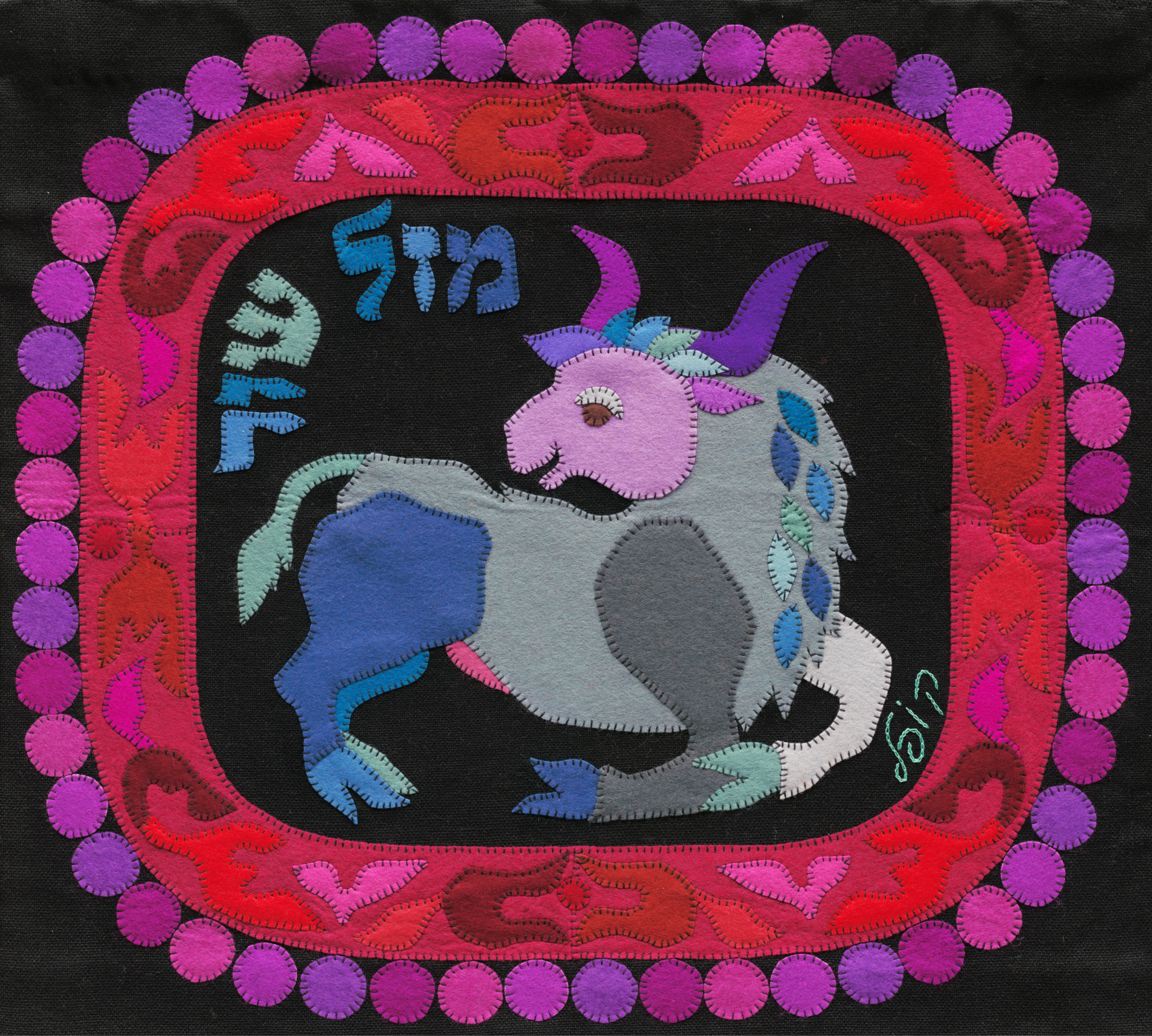 Taurus by Kopel Gurwin, a hand-cut felt appliqué depicting a stylized bull in pale grey, blue, and lavender against a deep black background, framed by a vivid ornamental border in red, pink, and purple tones. Hebrew lettering identifies the zodiac sign as Mazal Shor.