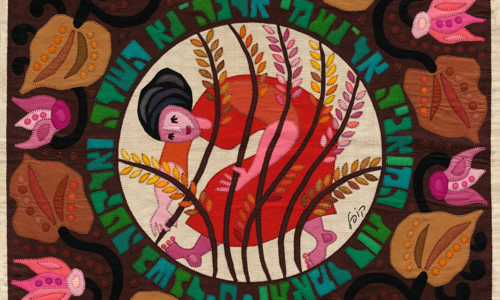 Felt wall hanging. Inside a circle of pale linen, a woman with dark hair and a red dress bends among tall wheat stalks. A ring of green and teal Hebrew letters cut from felt surrounds the circle, on a dark brown ground with large brown leaves and pink flower buds, every piece edged in hand stitching.